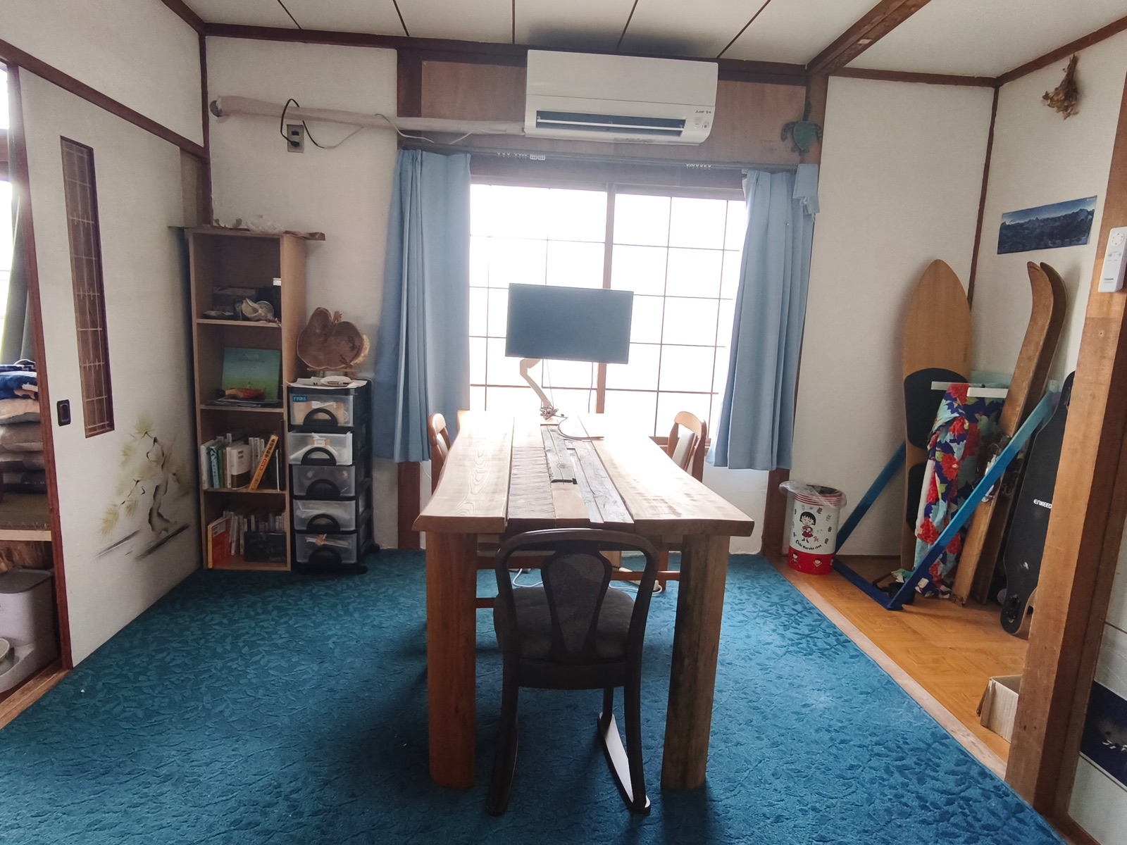 本棚とスキー板が並ぶ、窓のある共用の仕事部屋